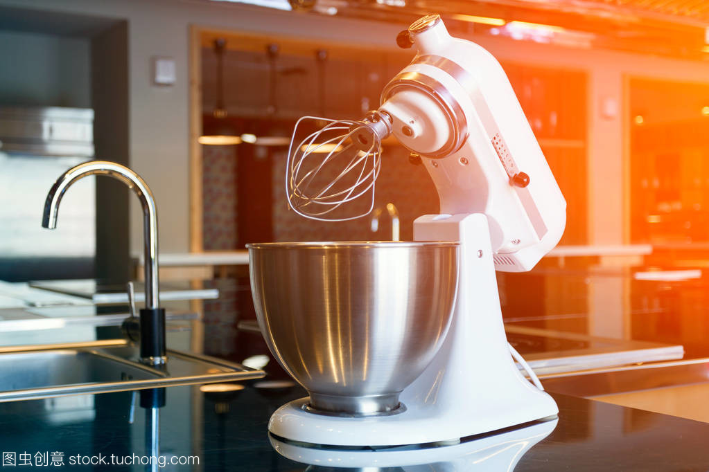 一個(gè)美麗的白色攪拌機(jī)與金屬杯站在現(xiàn)代廚房